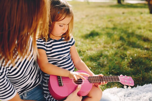 Mutter mit der Tochter, die in einem Sommerpark spielt