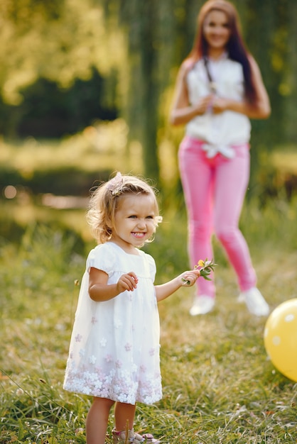 Mutter mit der Tochter, die in einem Sommerpark spielt