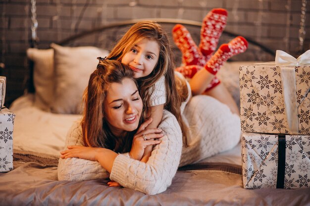 Mutter mit der Tochter, die zu Weihnachten im Bett liegt