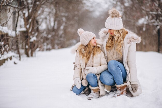 Mutter mit der Tochter, die zusammen in einen Winterpark geht