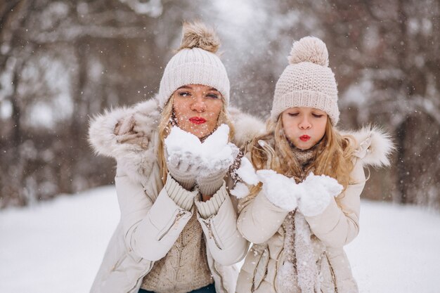 Mutter mit der Tochter, die zusammen in einen Winterpark geht