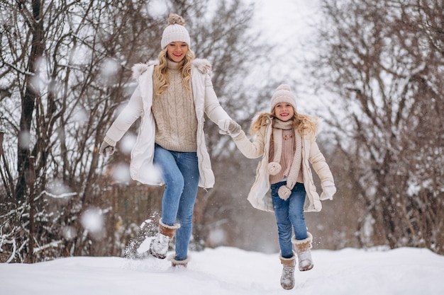 Mutter mit der Tochter, die zusammen in einen Winterpark geht