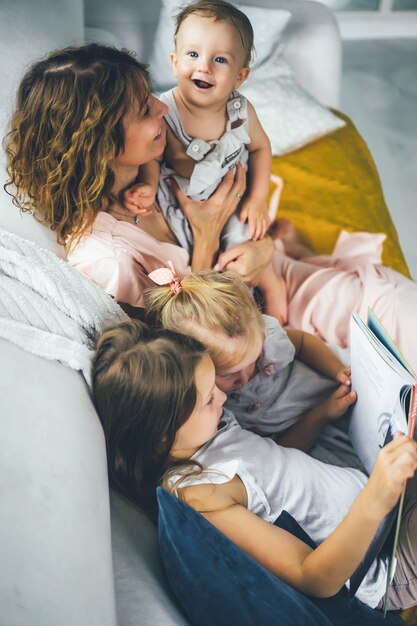 Mutter mit drei Kindern, die in gemütlicher Atmosphäre ein Buch lesen