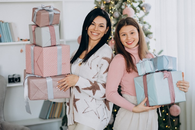 Mutter mit erwachsener Tochter mit Weihnachtsgeschenken durch Weihnachtsbaum