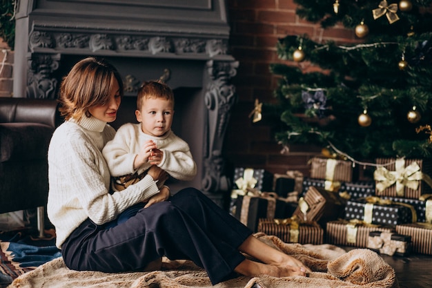 Mutter mit ihrem kleinen Sohn, der durch Weihnachtsbaum sitzt