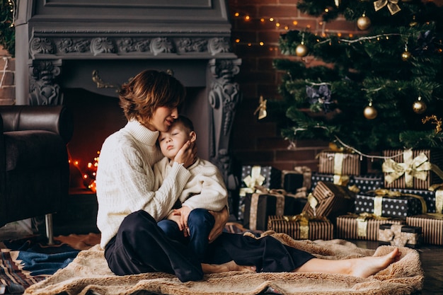 Mutter mit ihrem kleinen Sohn, der durch Weihnachtsbaum sitzt