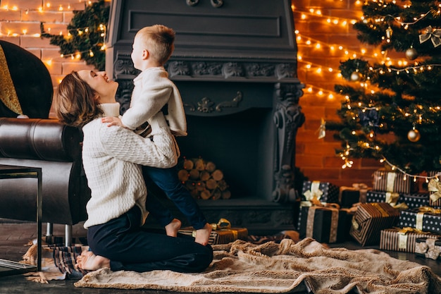 Mutter mit ihrem kleinen Sohn, der durch Weihnachtsbaum sitzt