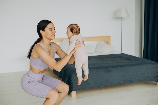 Mutter mit ihrer kleinen Tochter praktiziert Yoga zu Hause