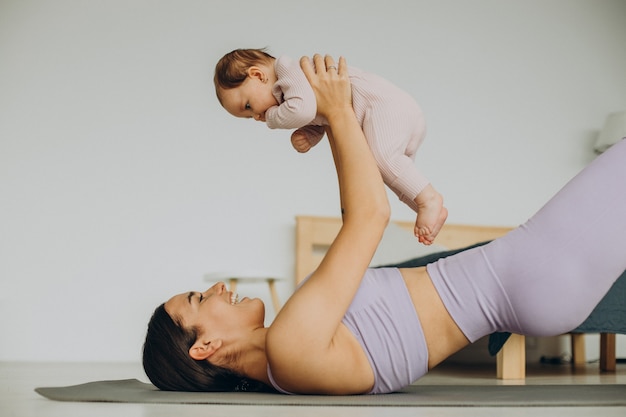 Mutter mit ihrer kleinen Tochter praktiziert Yoga zu Hause