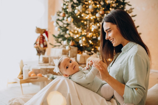 Mutter mit ihrer kleinen tochter sitzt am weihnachtsbaum