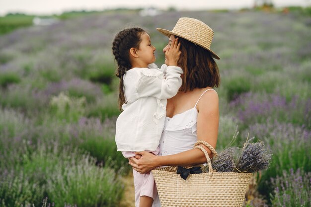 Mutter mit kleiner Tochter auf Lavendelfeld. Schöne Frau und niedliches Baby, das im Wiesenfeld spielt. Familienurlaub im Sommertag.