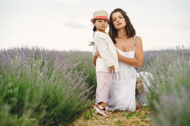 Mutter mit kleiner Tochter auf Lavendelfeld. Schöne Frau und niedliches Baby, das im Wiesenfeld spielt. Familienurlaub im Sommertag.