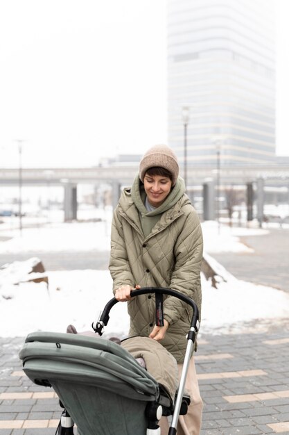 Mutter mit mittlerer Aufnahme, die mit Kinderwagen geht