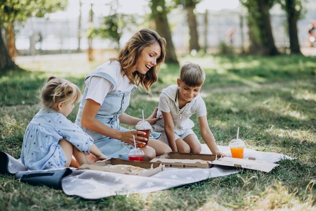 Mutter mit Sohn und Tochter essen Pizza im Park