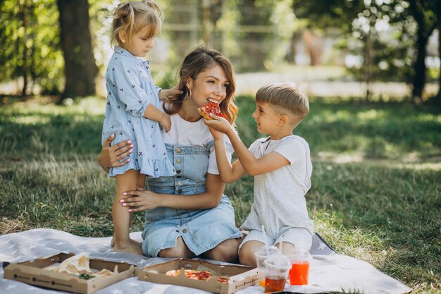 Mutter mit Sohn und Tochter essen Pizza im Park