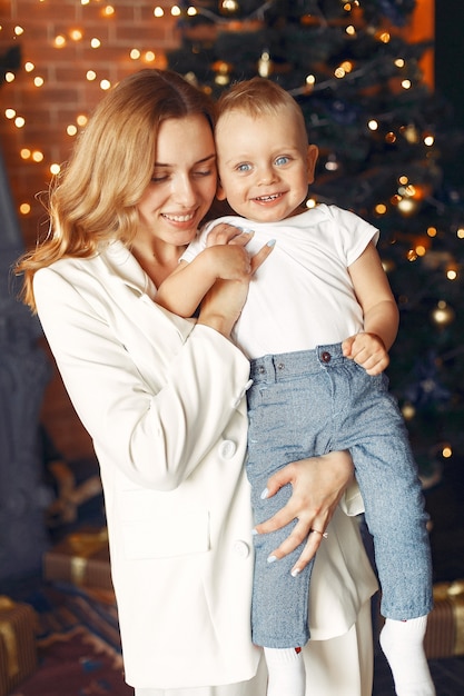 Mutter mit süßem Sohn zu Hause nahe Weihnachtsbaum