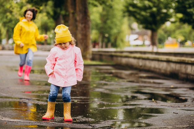 Mutter mit Tochter, die Spaß hat, in Pfützen zu springen