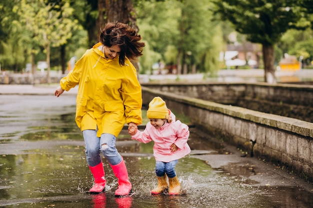 Mutter mit Tochter, die Spaß hat, in Pfützen zu springen