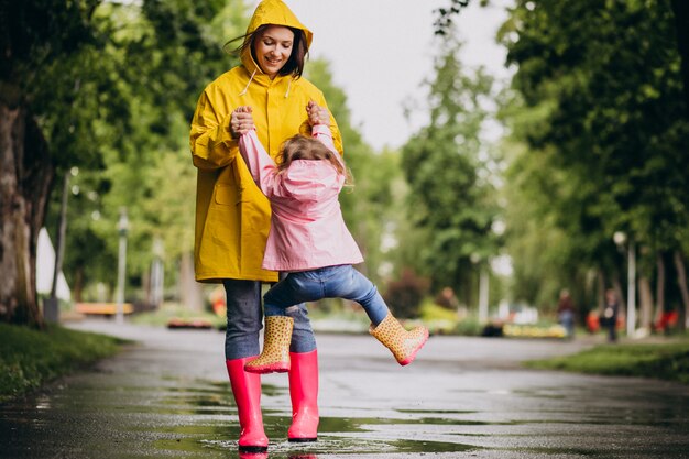 Mutter mit Tochter, die Spaß im Park bei regnerischem Wetter hat