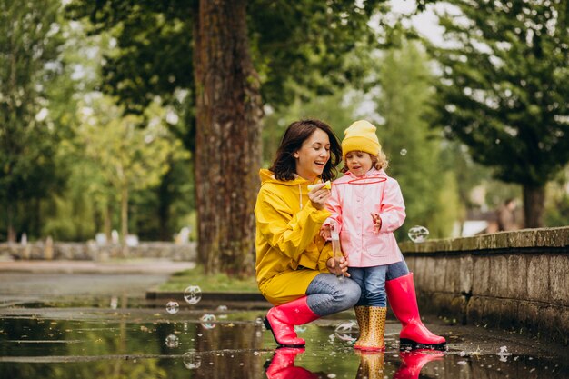 Mutter mit Tochter, die Spaß im Park bei regnerischem Wetter hat