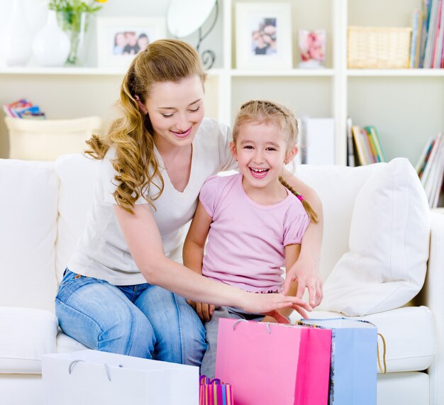 Mutter mit Tochter mit Einkaufstüten zu Hause