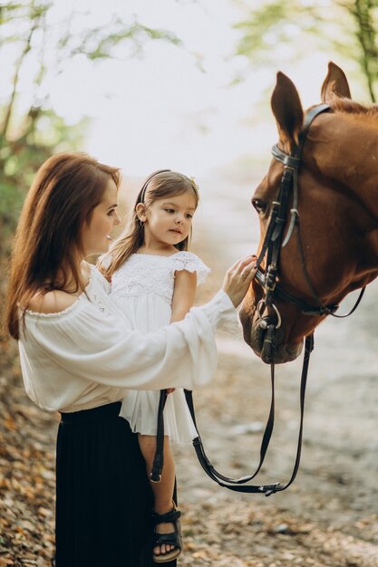 Mutter mit Tochter und Pferd im Wald