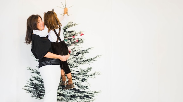 Kostenloses Foto mutter mit tochter vor weihnachtsbaum