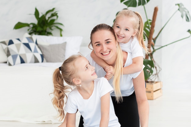 Mutter posiert glücklich mit Töchtern zu Hause