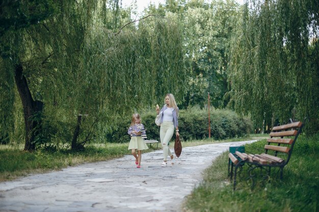 Mutter schaut auf einen Smartphone während ihre Tochter in einer Tablette in einem Park sieht