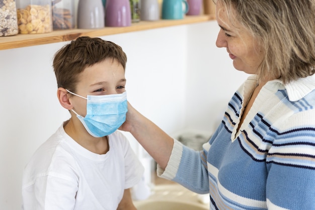 Mutter setzt ihrem Kind eine medizinische Maske auf