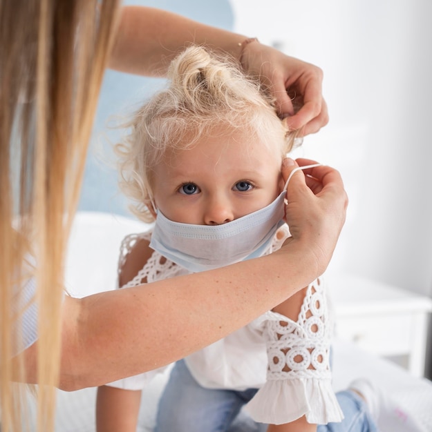 Mutter setzt medizinische Maske auf Kind auf