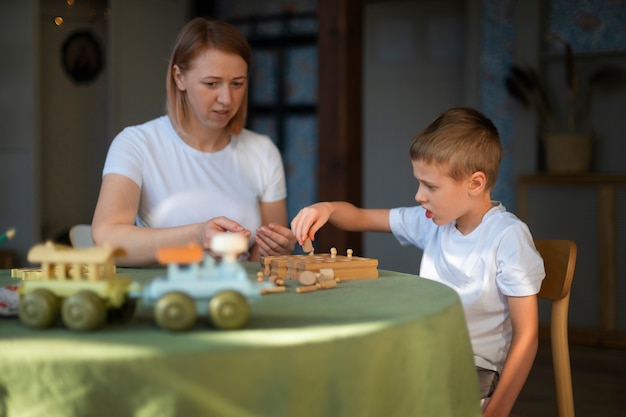 Mutter spielt mit ihrem autistischen Sohn mit Spielzeug