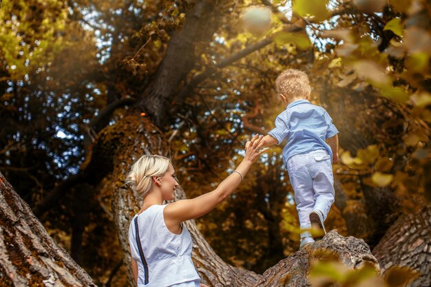 Mutter spielt mit ihrem Kind auf Baum im Park.