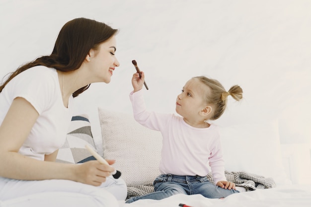 Mutter spielt mit Kosmetik im Bett mit ihrer Tochter