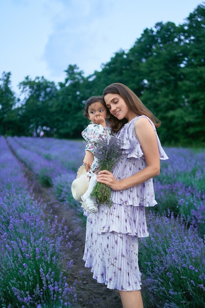 Mutter trägt kleine Tochter und Lavendelstrauß