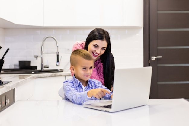 Mutter übersieht, als ihr sohn seinen laptop benutzt, um in ihrer küche zu lernen