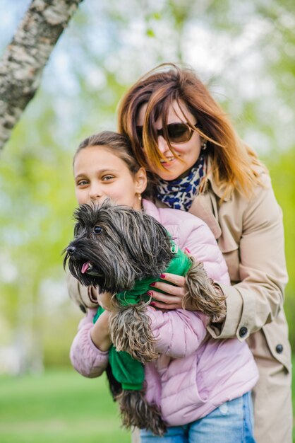 Mutter umarmt ihre Tochter und Hund im Freien