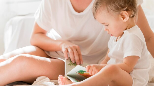 Mutter und Baby sitzen im Bett mit Buch