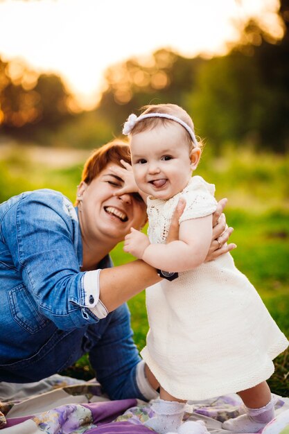 Mutter und Baby spielen auf der Decke auf grünem Rasen