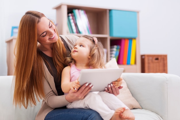 Mutter und Baby spielen zu Hause auf dem Tablet