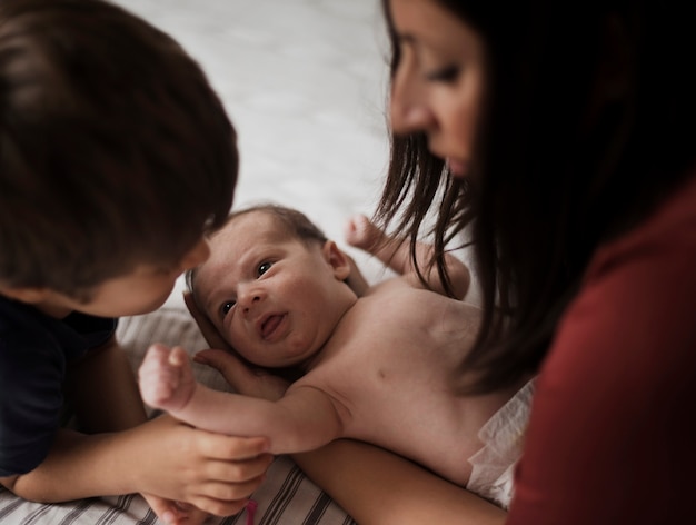 Mutter und großer Bruder, die kleines Baby aufpassen