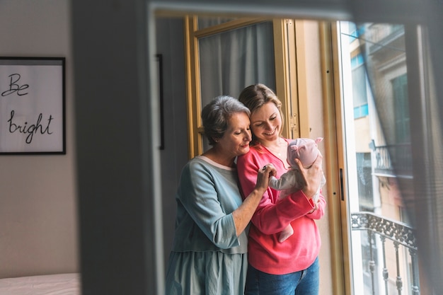 Kostenloses Foto mutter und großmutter mit baby vor fenster