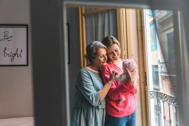 Mutter und Großmutter mit Baby vor Fenster