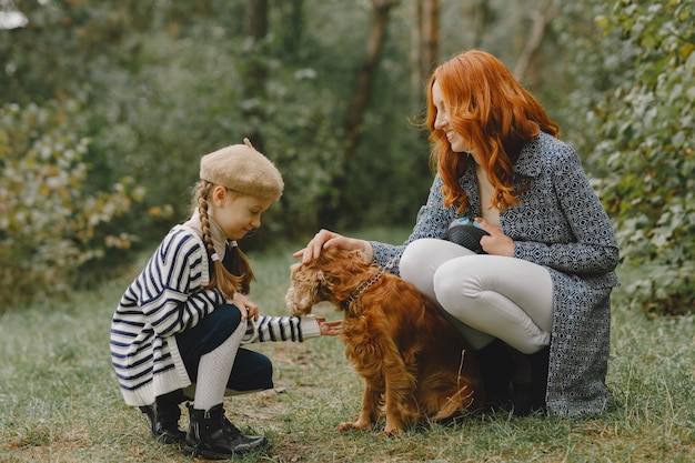 Mutter und ihre Tochter spielen mit Hund. Familie im Herbstpark. Haustier-, Haustier- und Lebensstilkonzept. Herbstzeit.