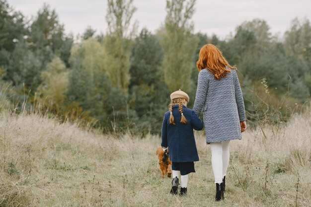 Mutter und ihre Tochter spielen mit Hund. Familie im Herbstpark. Haustier-, Haustier- und Lebensstilkonzept. Herbstzeit.