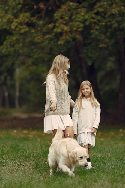 Mutter und ihre Tochter spielen mit Hund. Familie im Herbstpark. Haustier-, Haustier- und Lebensstilkonzept