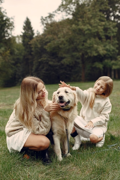 Mutter und ihre Tochter spielen mit Hund. Familie im Herbstpark. Haustier-, Haustier- und Lebensstilkonzept