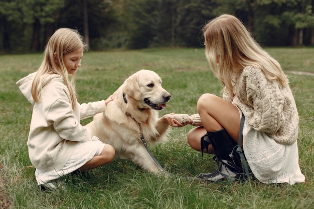 Mutter und ihre Tochter spielen mit Hund. Familie im Herbstpark. Haustier-, Haustier- und Lebensstilkonzept