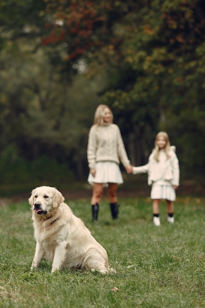 Mutter und ihre Tochter spielen mit Hund. Familie im Herbstpark. Haustier-, Haustier- und Lebensstilkonzept