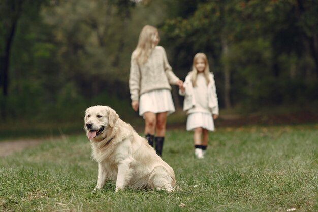 Mutter und ihre Tochter spielen mit Hund. Familie im Herbstpark. Haustier-, Haustier- und Lebensstilkonzept